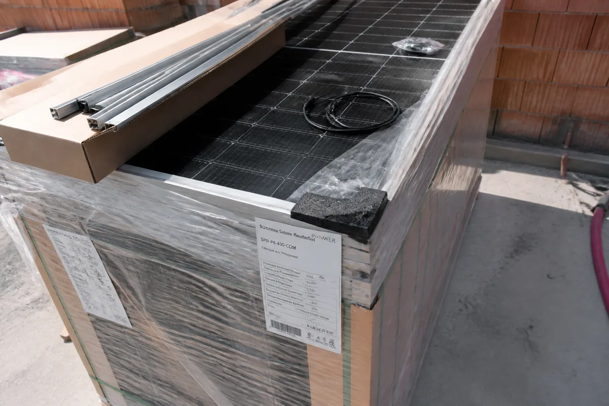 Panneaux photovoltaïques et cornières de fixation en cours de déballage pour comparer un kit solaire